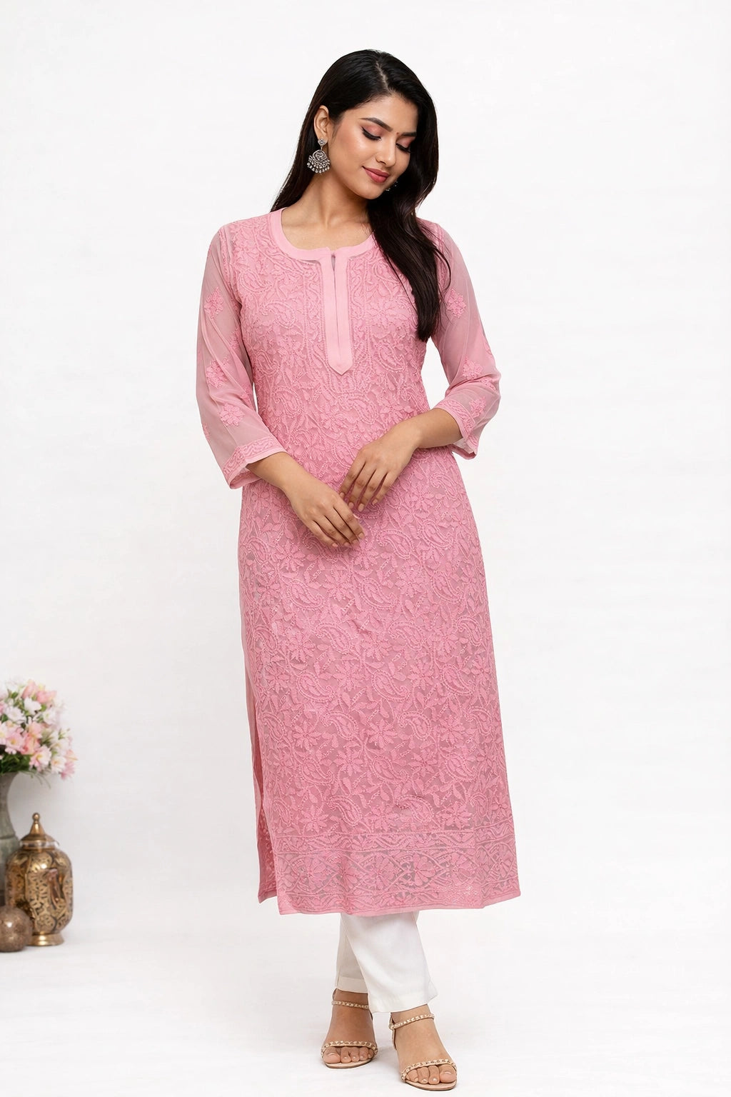 Woman wearing a lucknowi chikankari pink kurta with white pants on a white background