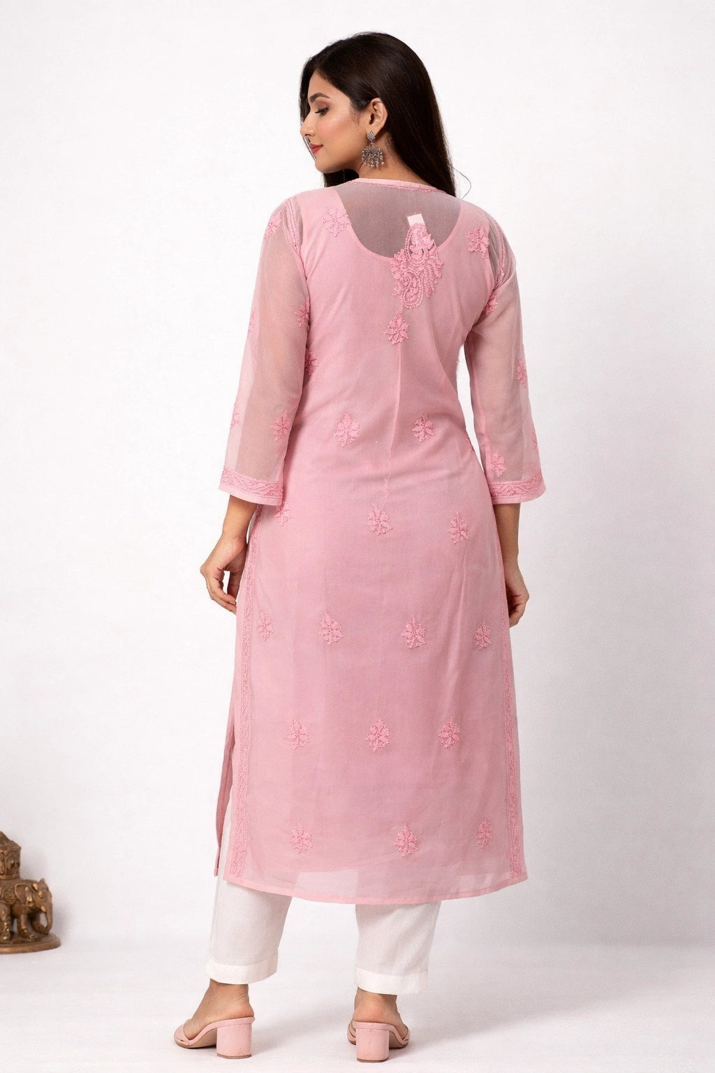 Woman wearing a chikan pink kurta with white pants on a white background