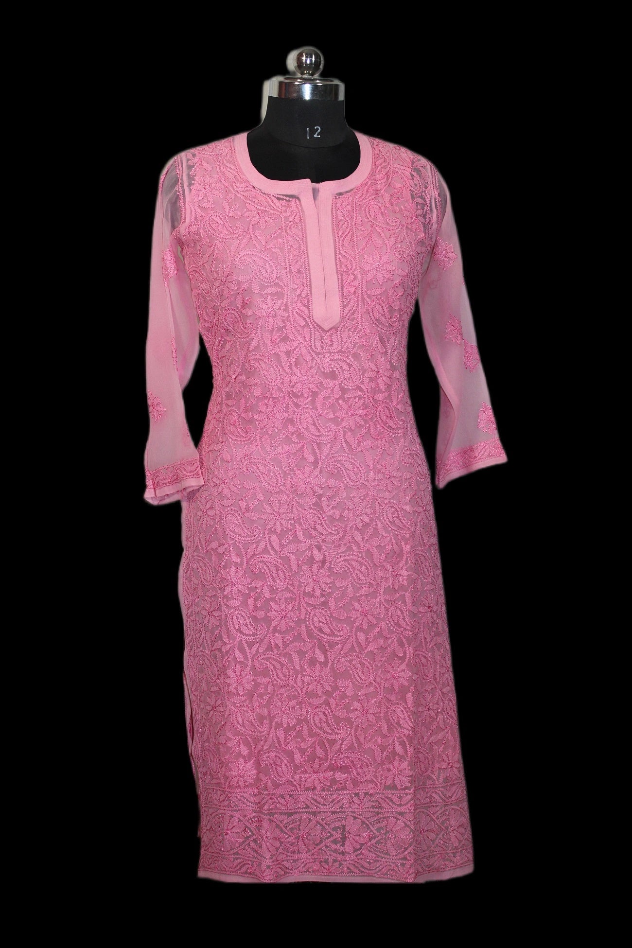 Pink embroidered dress on a mannequin against a black background