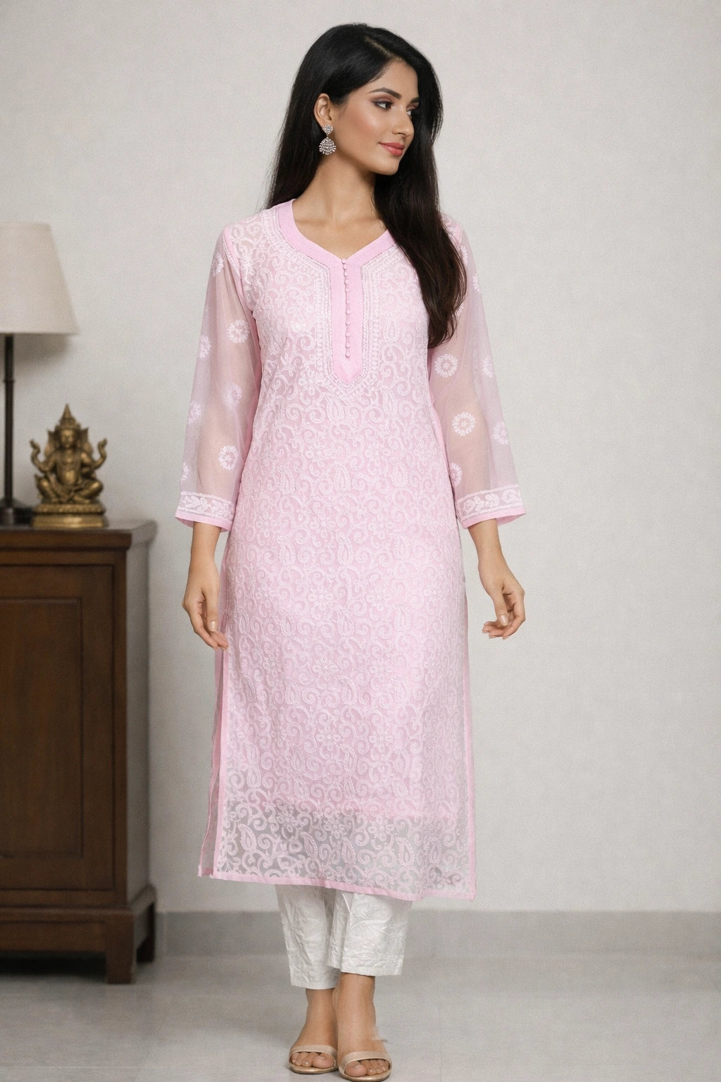 Woman wearing a lucknowi chikankari light pink kurta with white pants in a minimalistic room.