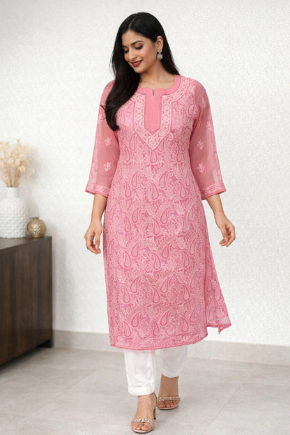 Woman wearing a pink embroidered kurta with white pants against a white background