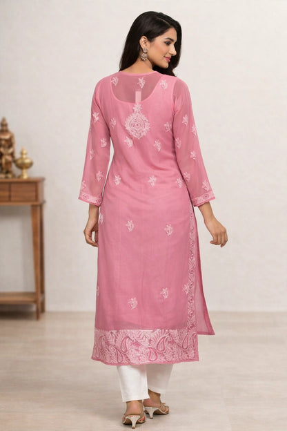 Woman wearing a pink embroidered kurta with white pants against a neutral background