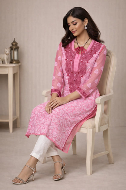 Woman wearing a lucknowi chikankari pink traditional outfit sitting on a chair.