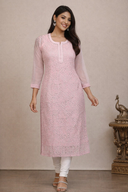 Woman wearing a light pink kurta with white pants against a neutral background