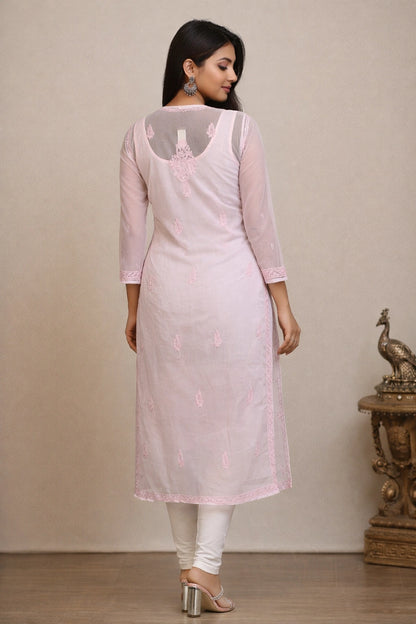 Woman wearing a light pink kurta with white pants against a beige background