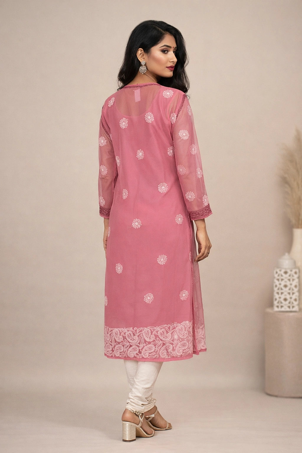 Woman wearing a pink kurta with white patterns and lace details on a beige background