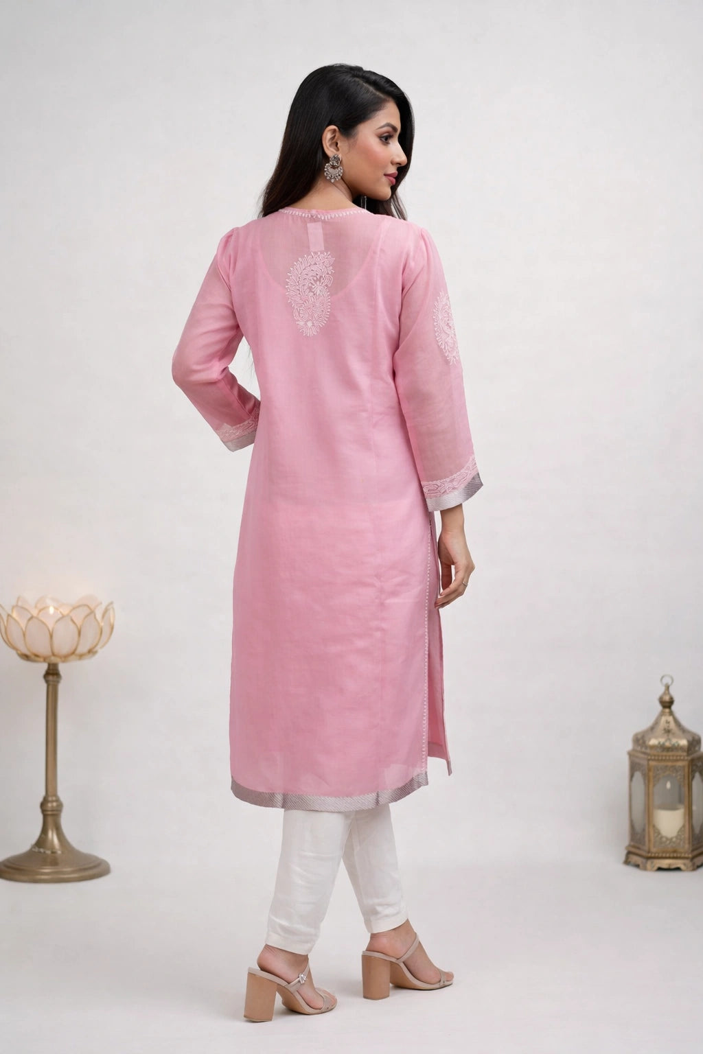Woman wearing a chikan pink kurta with white pants on a white background