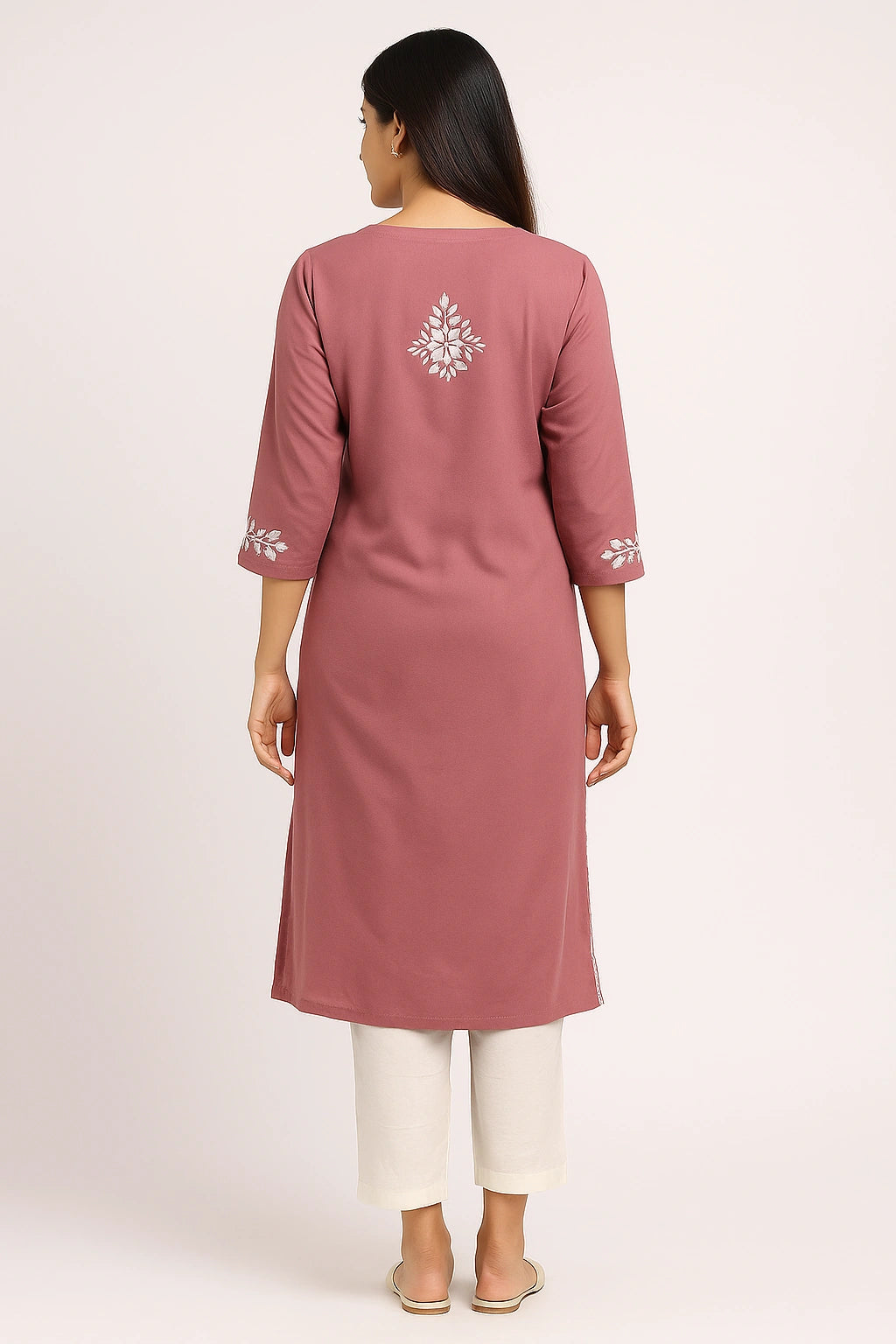 Woman wearing a mauve kurta with white embroidery on a light pink background