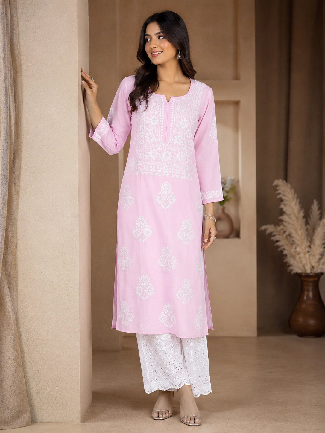 lucknowi chikankari Woman wearing a pink kurta with white pants in a neutral setting