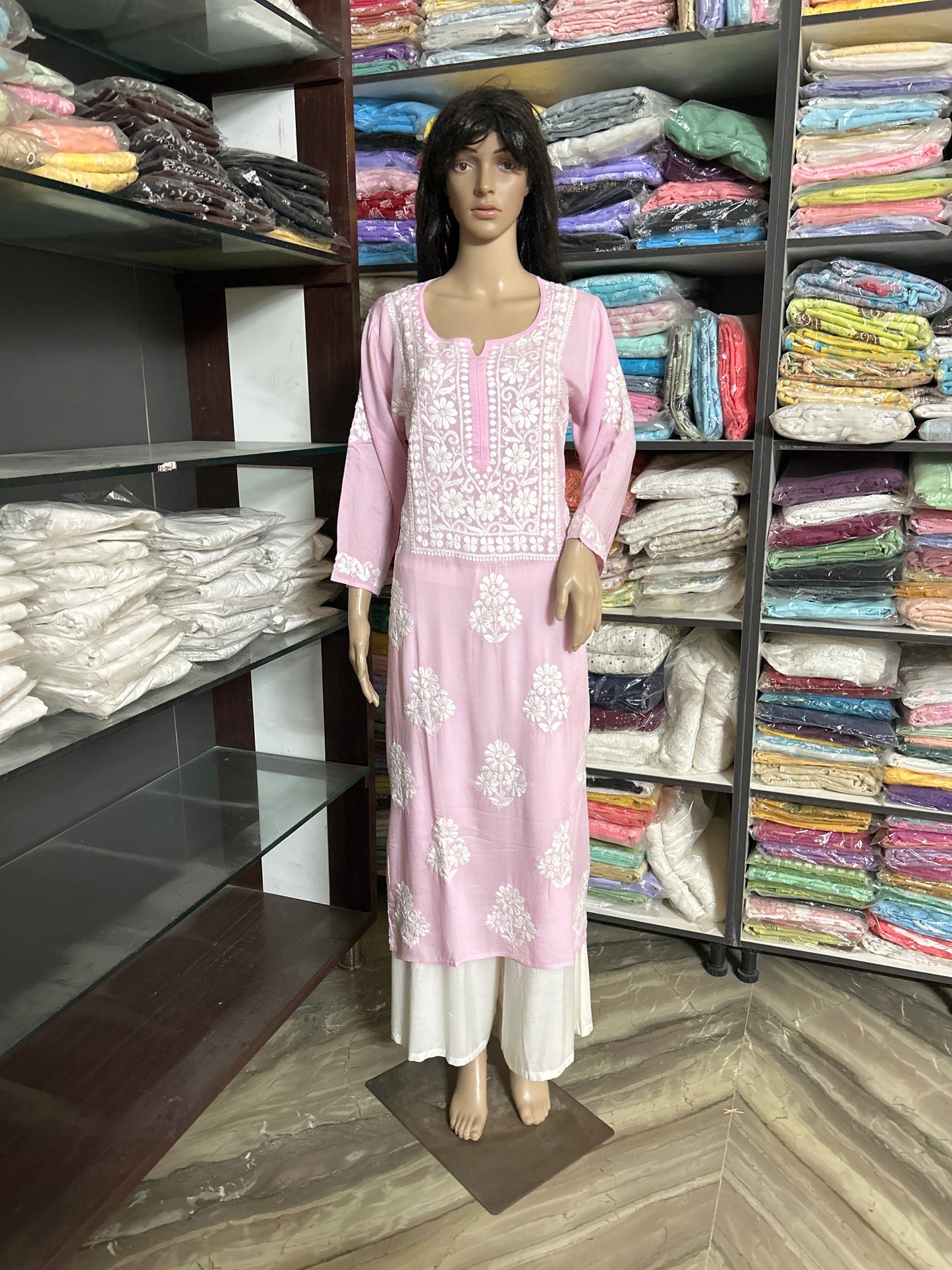 lucknowi chikankari Mannequin wearing a pink and white floral dress in a fabric store.