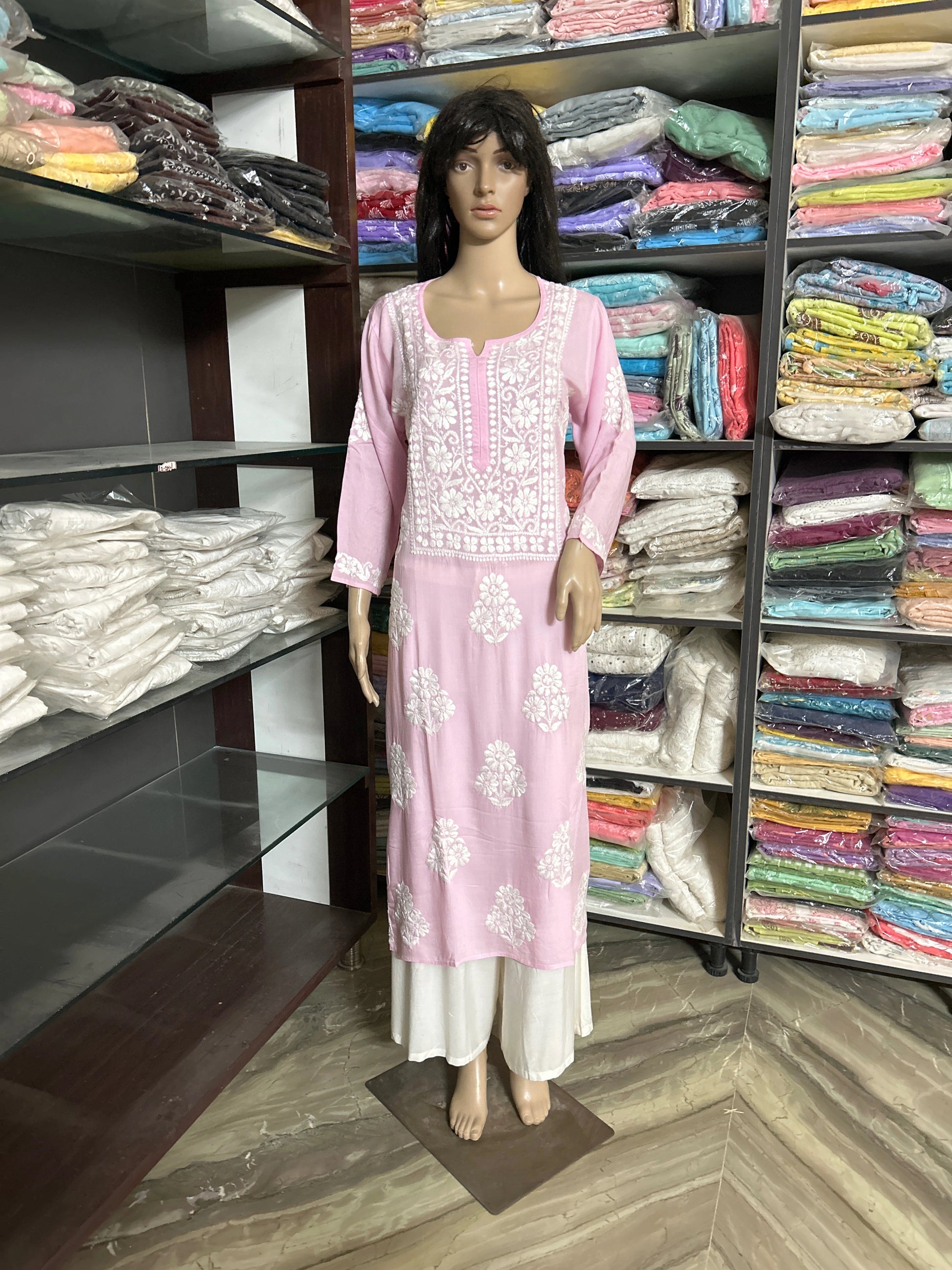lucknowi chikankari Mannequin wearing a pink and white floral dress in a fabric store.