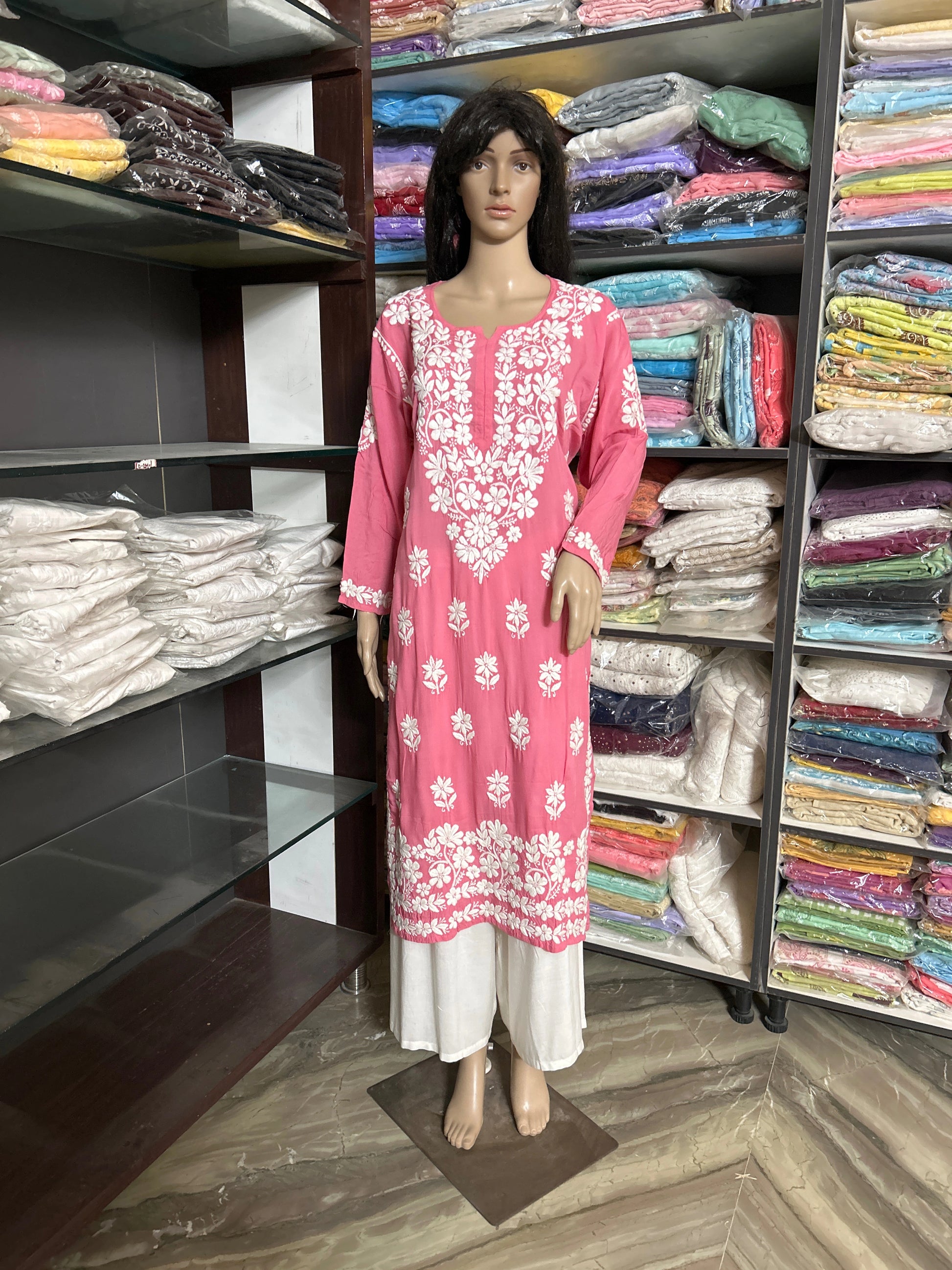 lucknowi chikankari Mannequin wearing a pink and white floral dress in a fabric store.