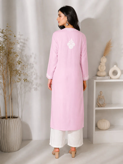 lucknowi chikankari Woman wearing a pink kurta with white pants in a minimalistic room.