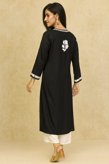 Woman wearing a black kurta with white embroidery on a beige background