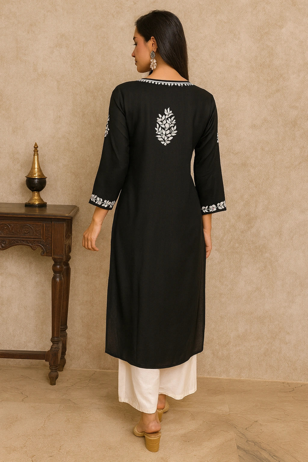 Woman wearing a black kurta with white embroidery in a neutral setting