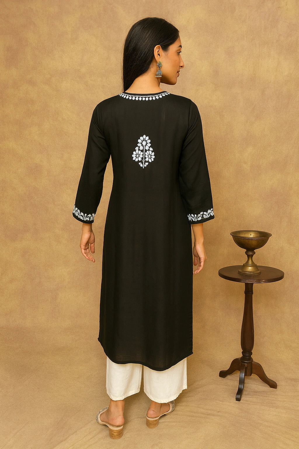 Woman wearing a black kurta with white embroidery on a beige background
