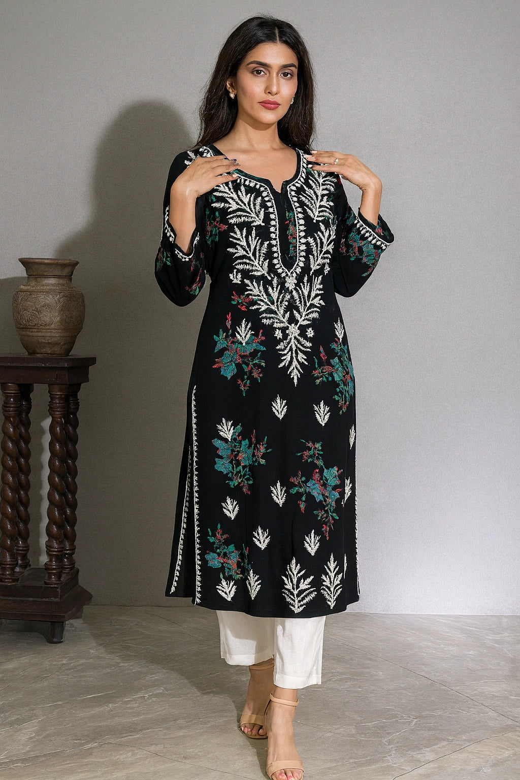 lucknowi chikankari Woman wearing a black and white embroidered kurta with white pants on a beige background