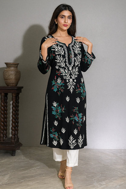 lucknowi chikankari Woman wearing a black and white embroidered kurta with white pants on a beige background