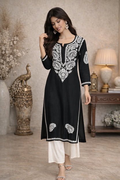 Woman wearing a black and white embroidered kurta in an indoor setting.