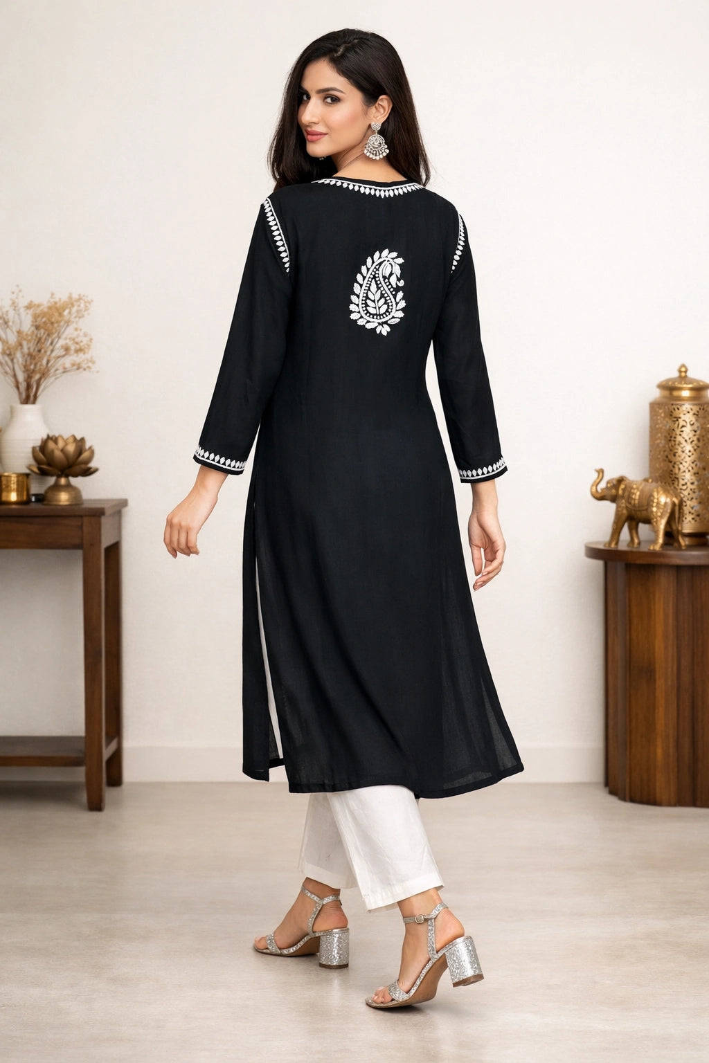 Woman wearing a black kurta with white embroidery in a minimalistic setting.
