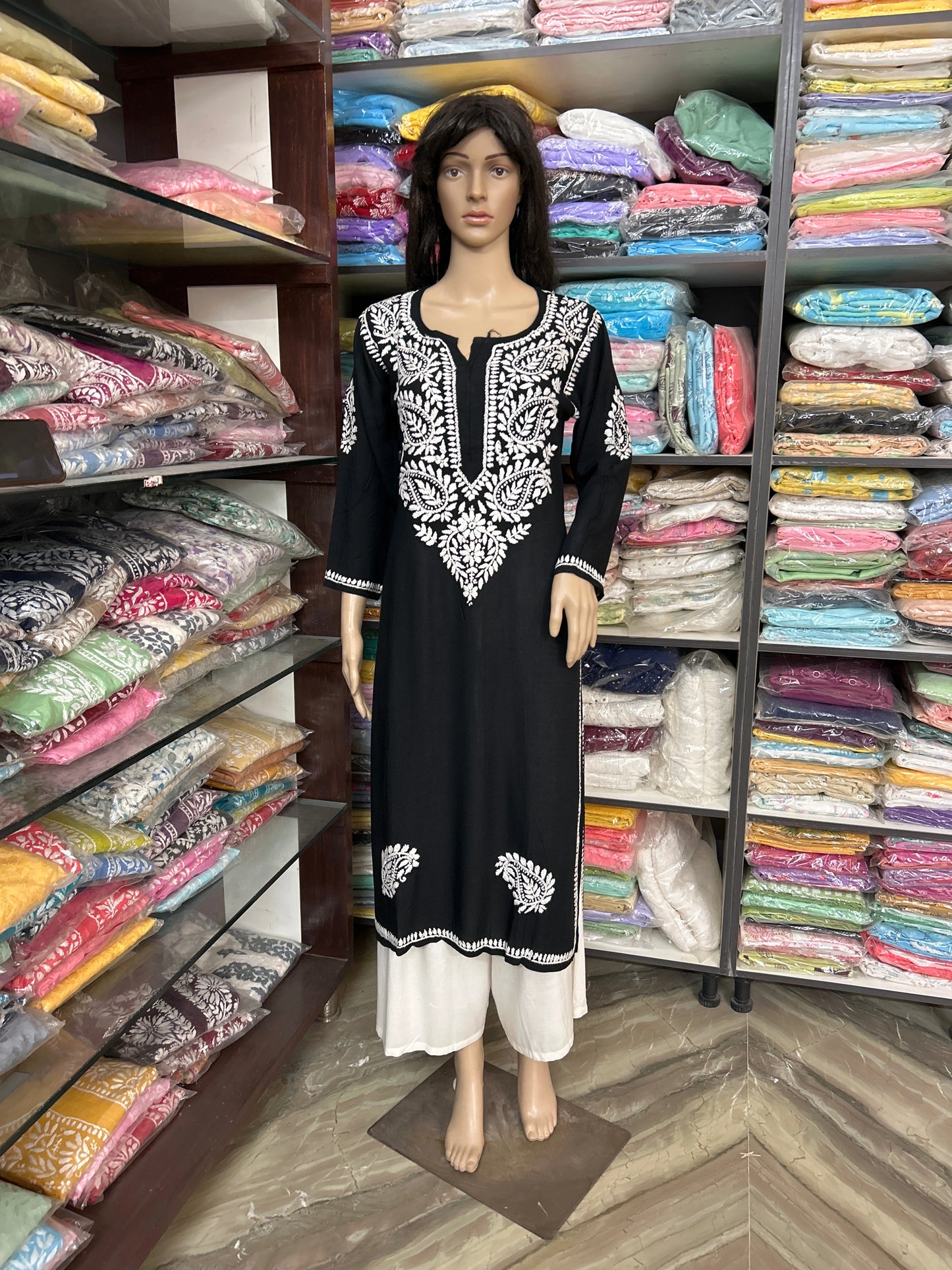 Mannequin wearing a black and white embroidered dress in a fabric store.