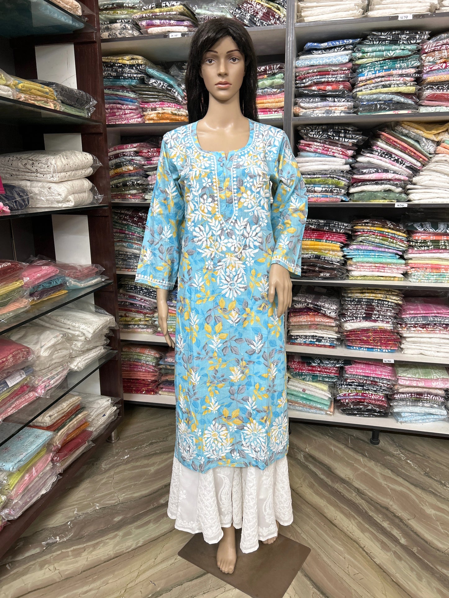 Mannequin wearing a lucknowi chikankari blue floral dress in a fabric store