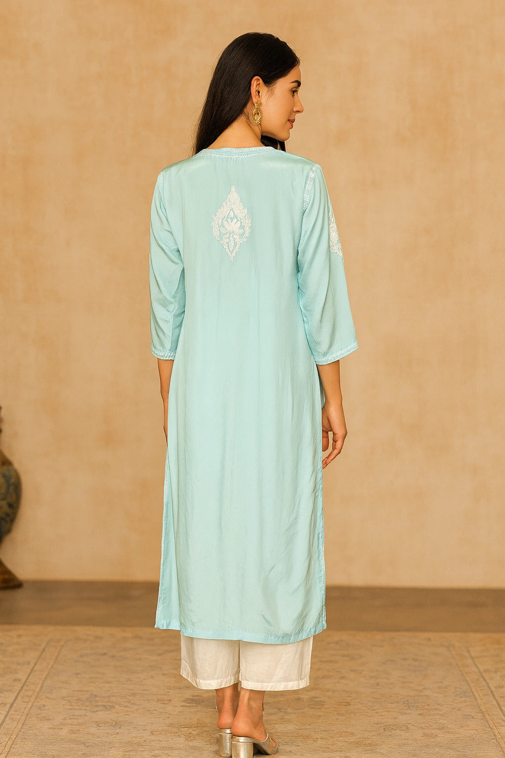 Woman wearing a light blue kurta with white embroidery on a beige background