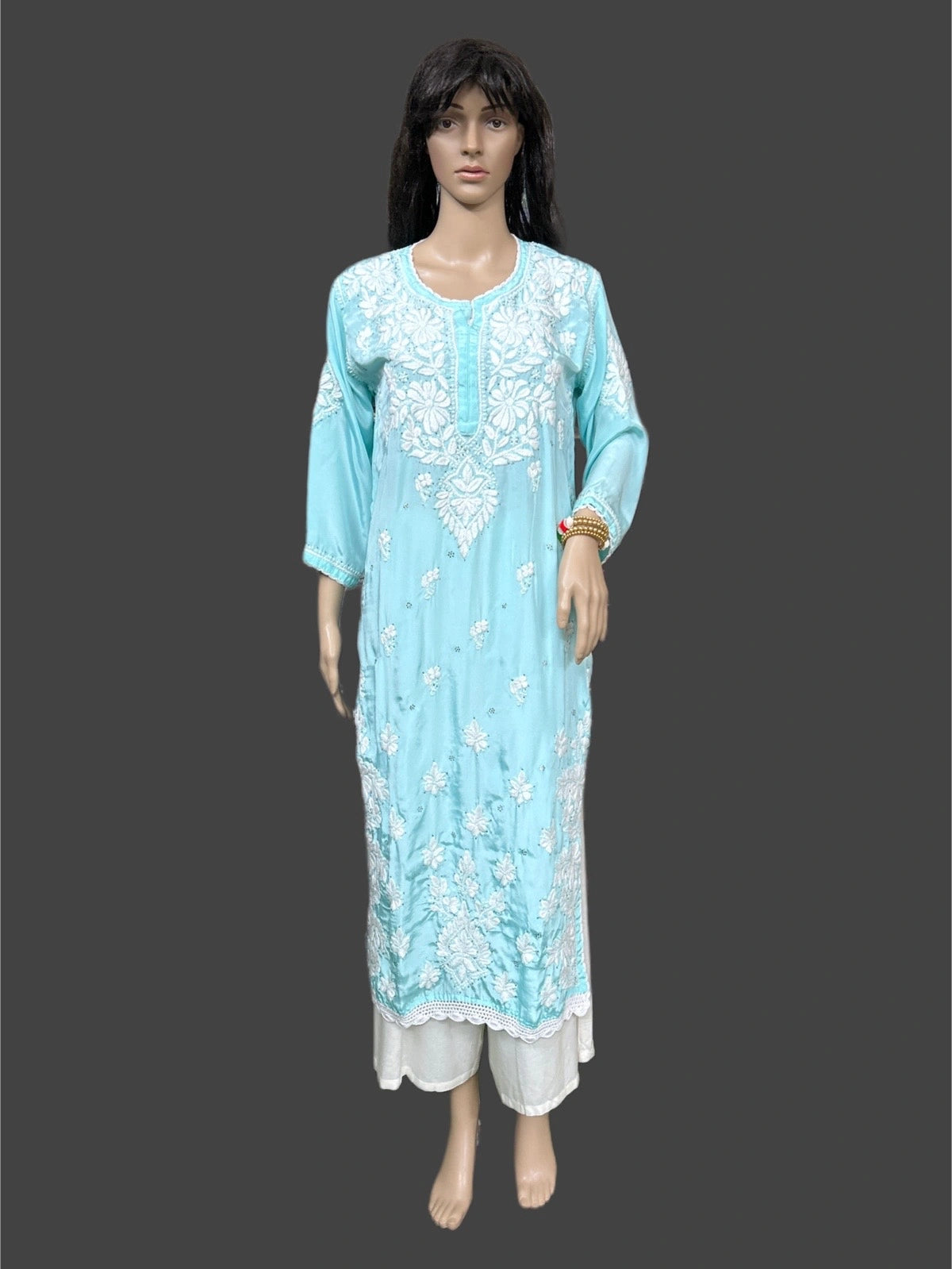Light blue embroidered dress on a mannequin against a dark background