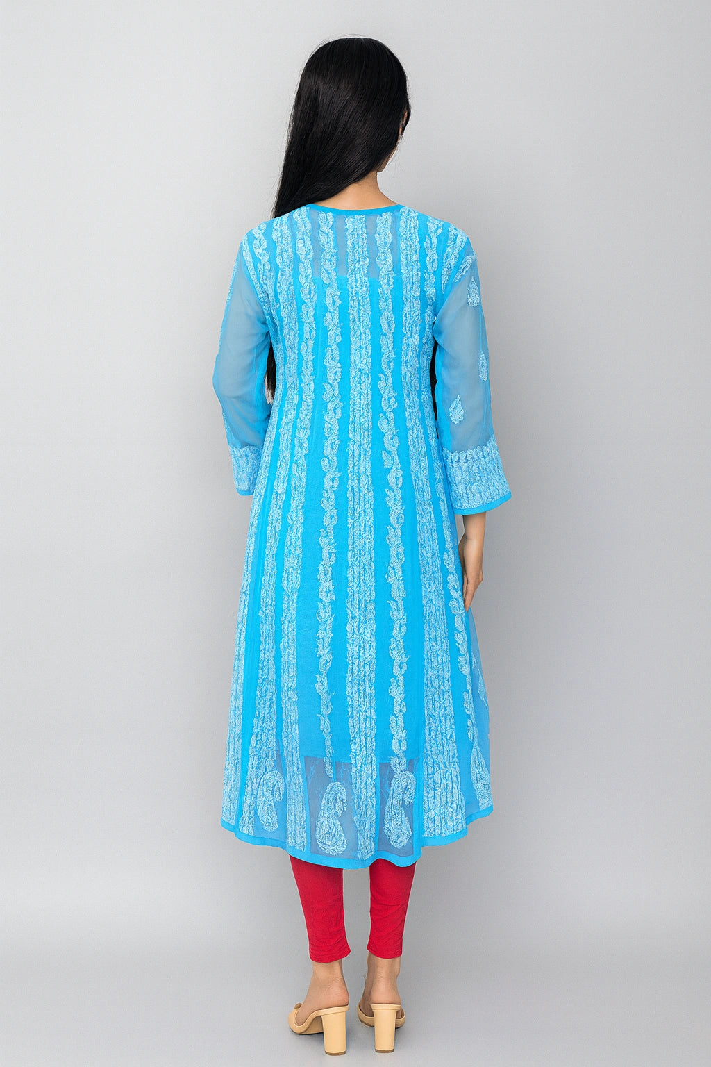 lucknowi chikankari Woman wearing a light blue kurta with white pants in a minimalistic setting.