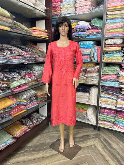 lucknowi chikankari Mannequin wearing a red dress in a fabric store with shelves of colorful fabrics.