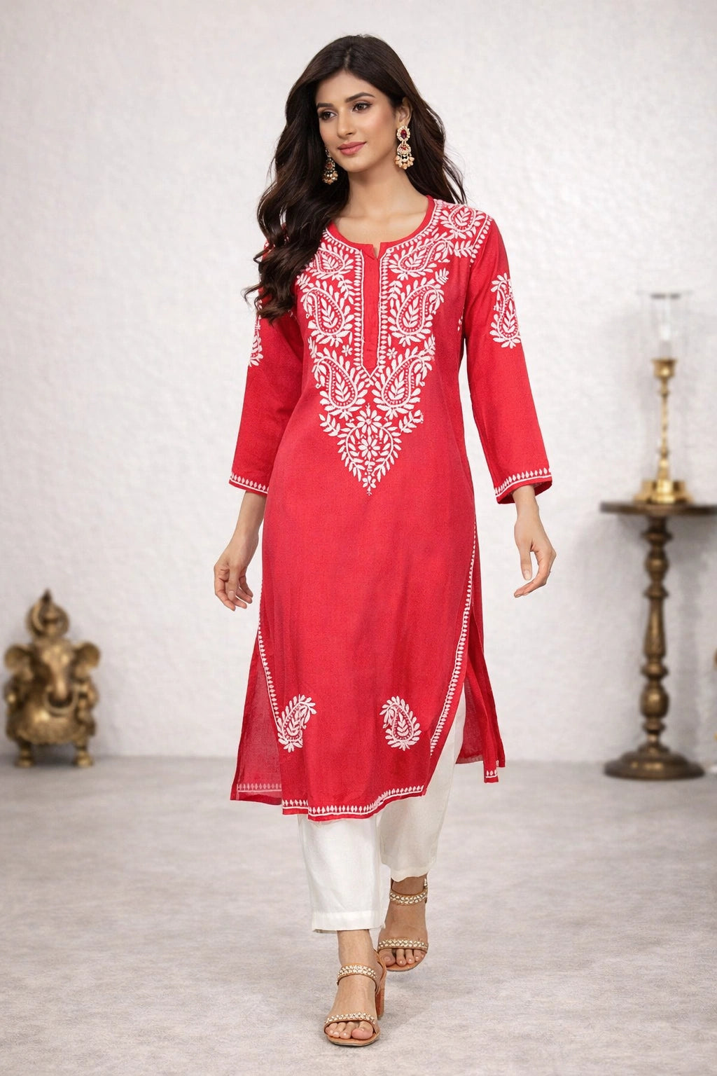 Woman wearing a red embroidered kurta with white pants in a minimalistic setting.