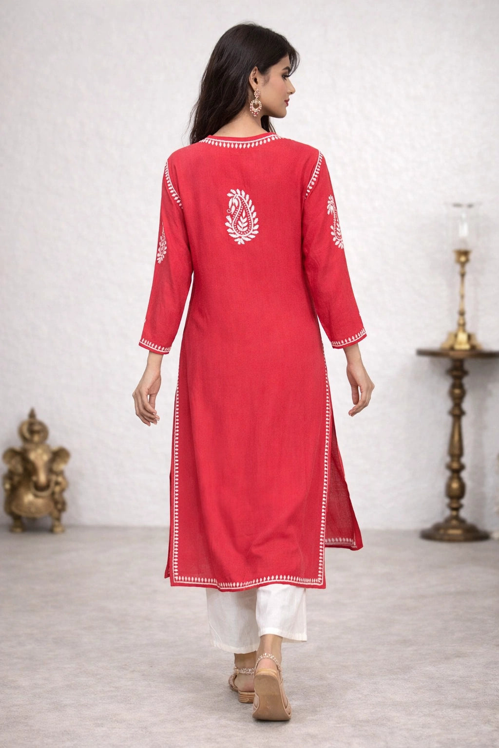 Woman wearing a red kurta with white embroidery in a minimalistic setting.