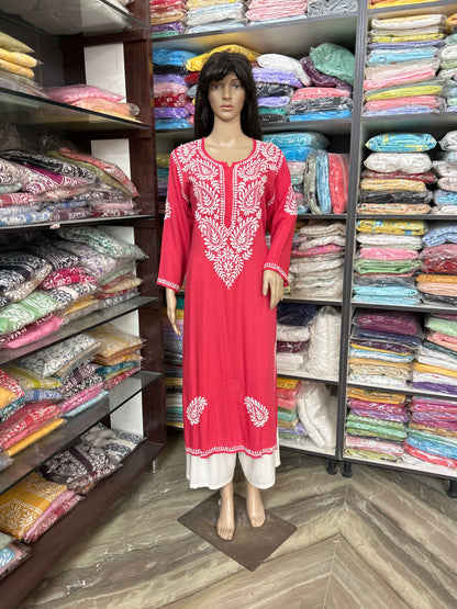 Mannequin wearing a red dress with white embroidery in a fabric store.
