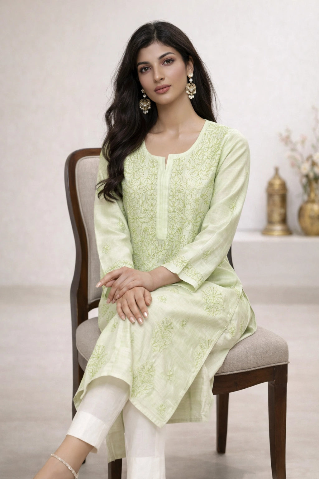 Woman wearing a lucknowi chikankari light green floral kurta with white pants on a white background