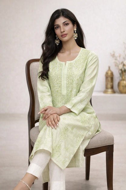 Woman wearing a lucknowi chikankari light green floral kurta with white pants on a white background