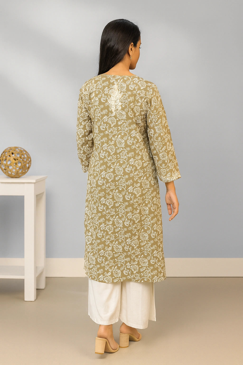 lucknowi chikankari Woman wearing a green floral kurta with white pants in a minimal indoor setting.