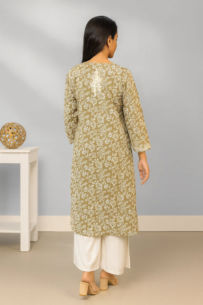 lucknowi chikankari Woman wearing a green floral kurta with white pants in a minimal indoor setting.