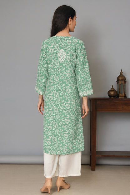 lucknowi chikankari Woman wearing a green floral kurta with white pants in a minimalistic room.