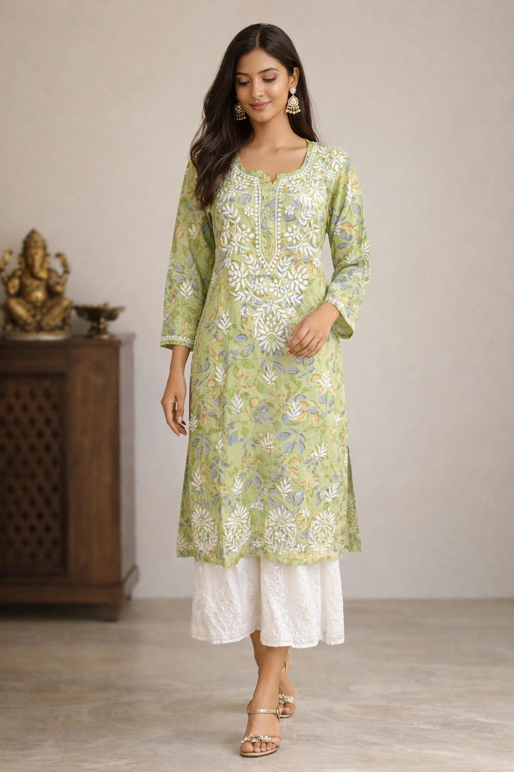 Woman wearing a lucknowi chikankari green floral kurta with white pants in a room setting.