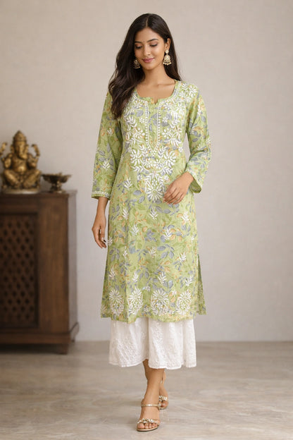 Woman wearing a lucknowi chikankari green floral kurta with white pants in a room setting.