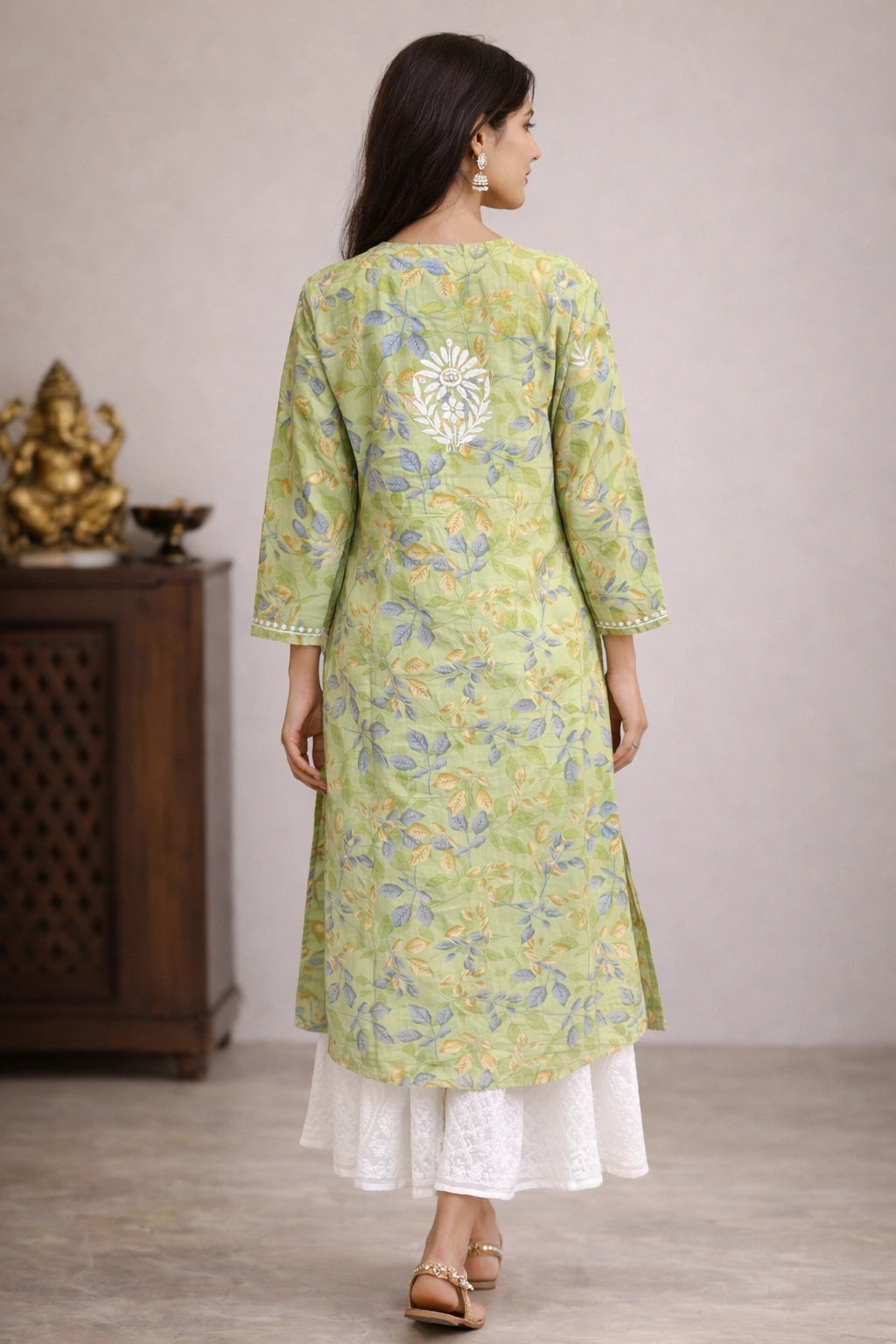 Woman wearing a lucknowi chikankari green floral kurta with white pants in a minimal indoor setting.