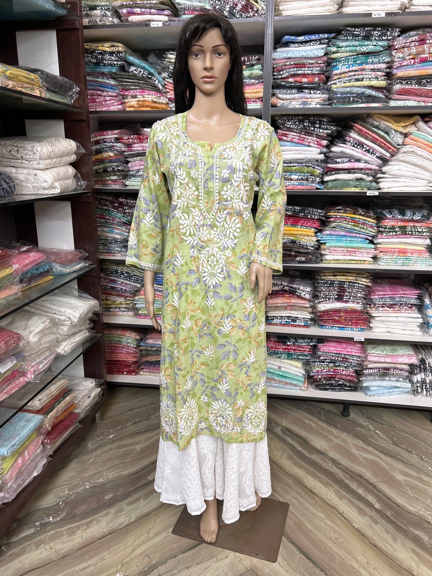 Mannequin wearing a lucknowi chikankari green floral dress in a fabric store