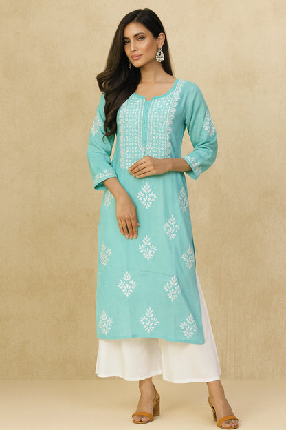 Woman wearing a light blue embroidered kurta with white pants on a beige background