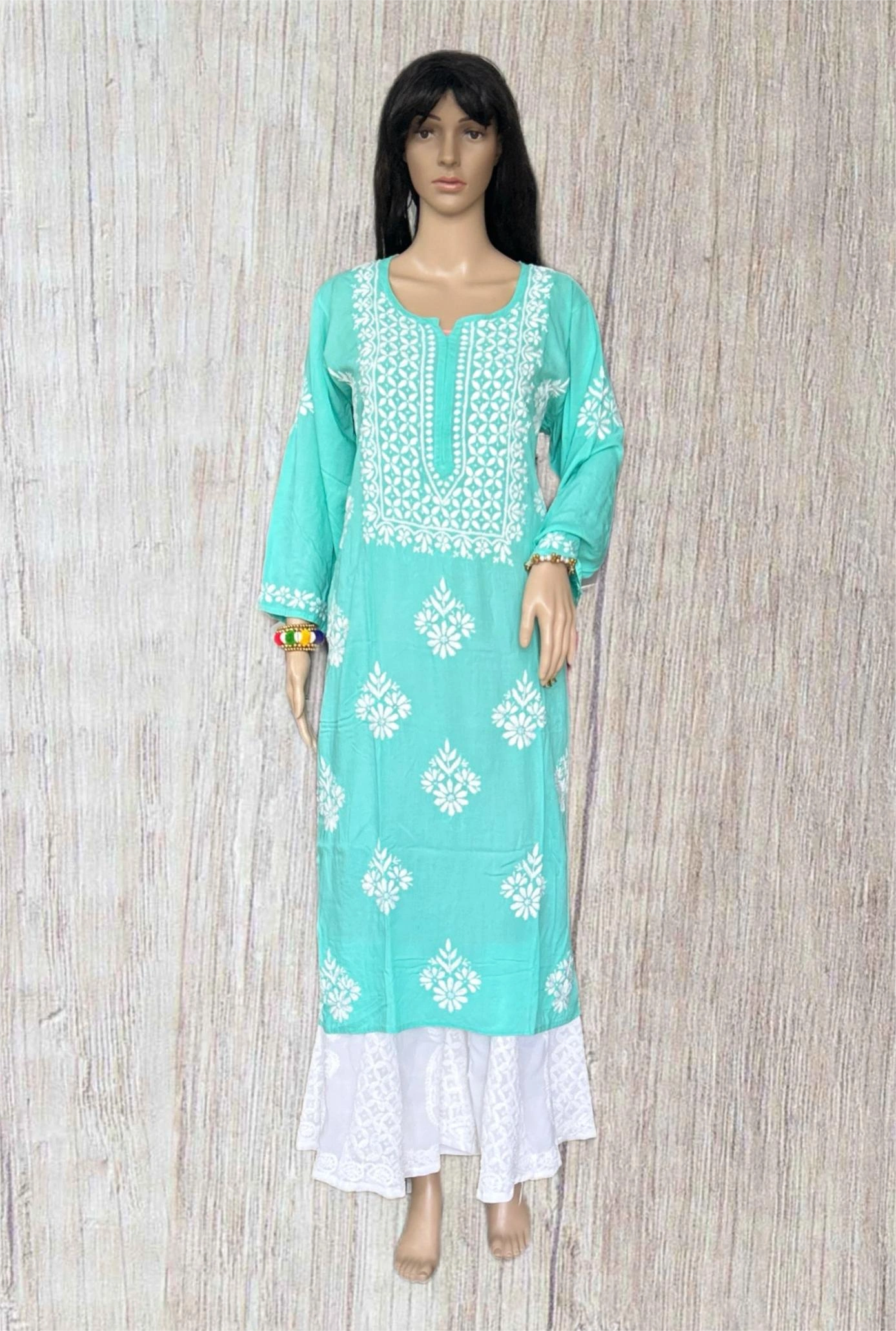 Turquoise and white embroidered dress on a wooden background