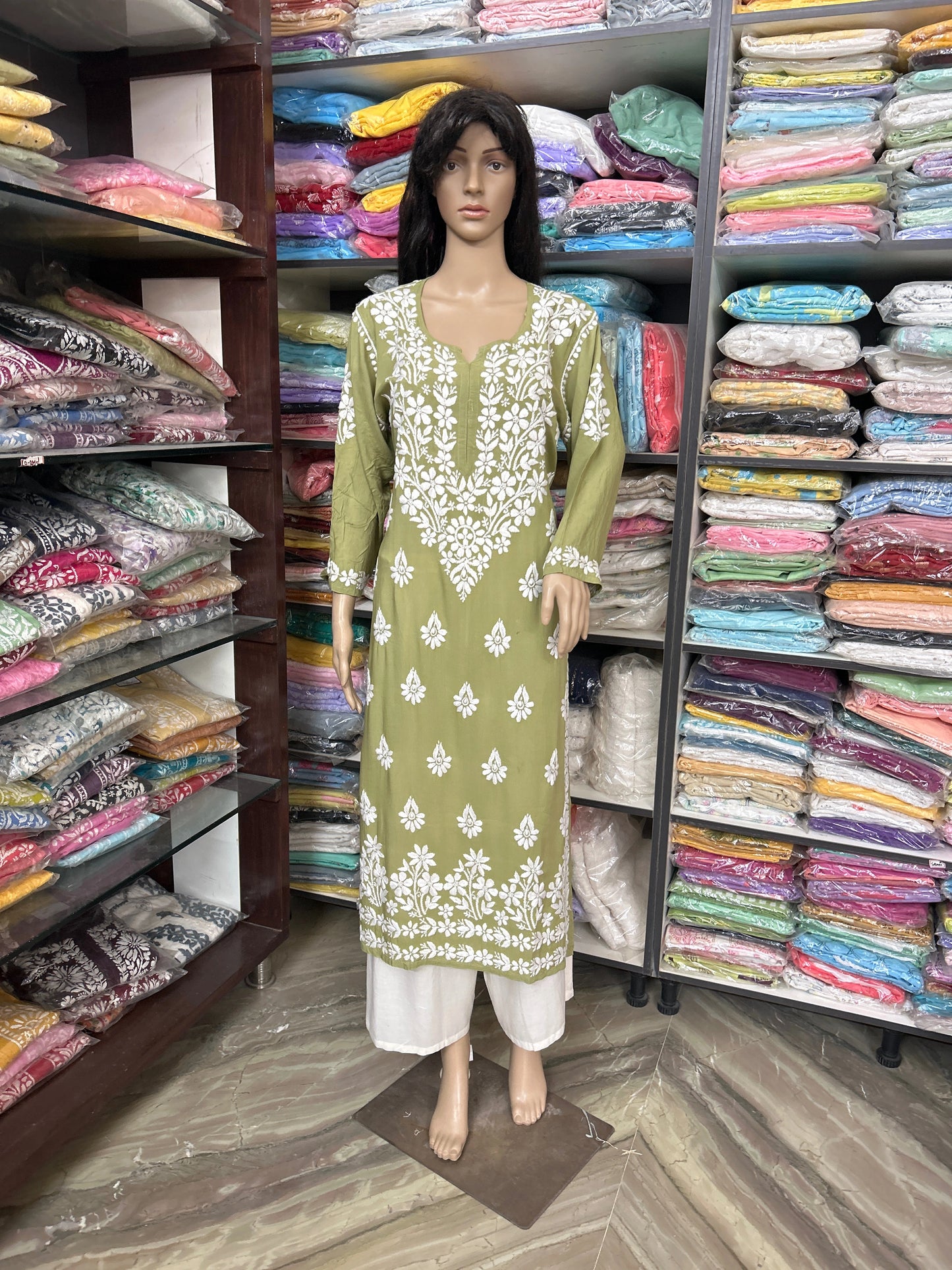 Mannequin wearing a green and white embroidered kurta in a fabric store.