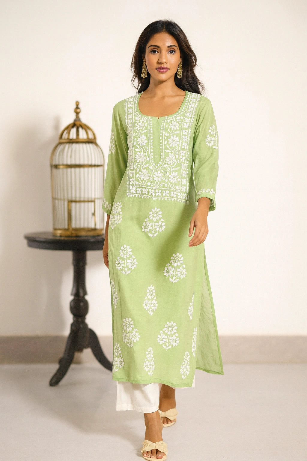 Lucknowi Chikankari Woman wearing a light green kurta with white floral patterns on a plain background