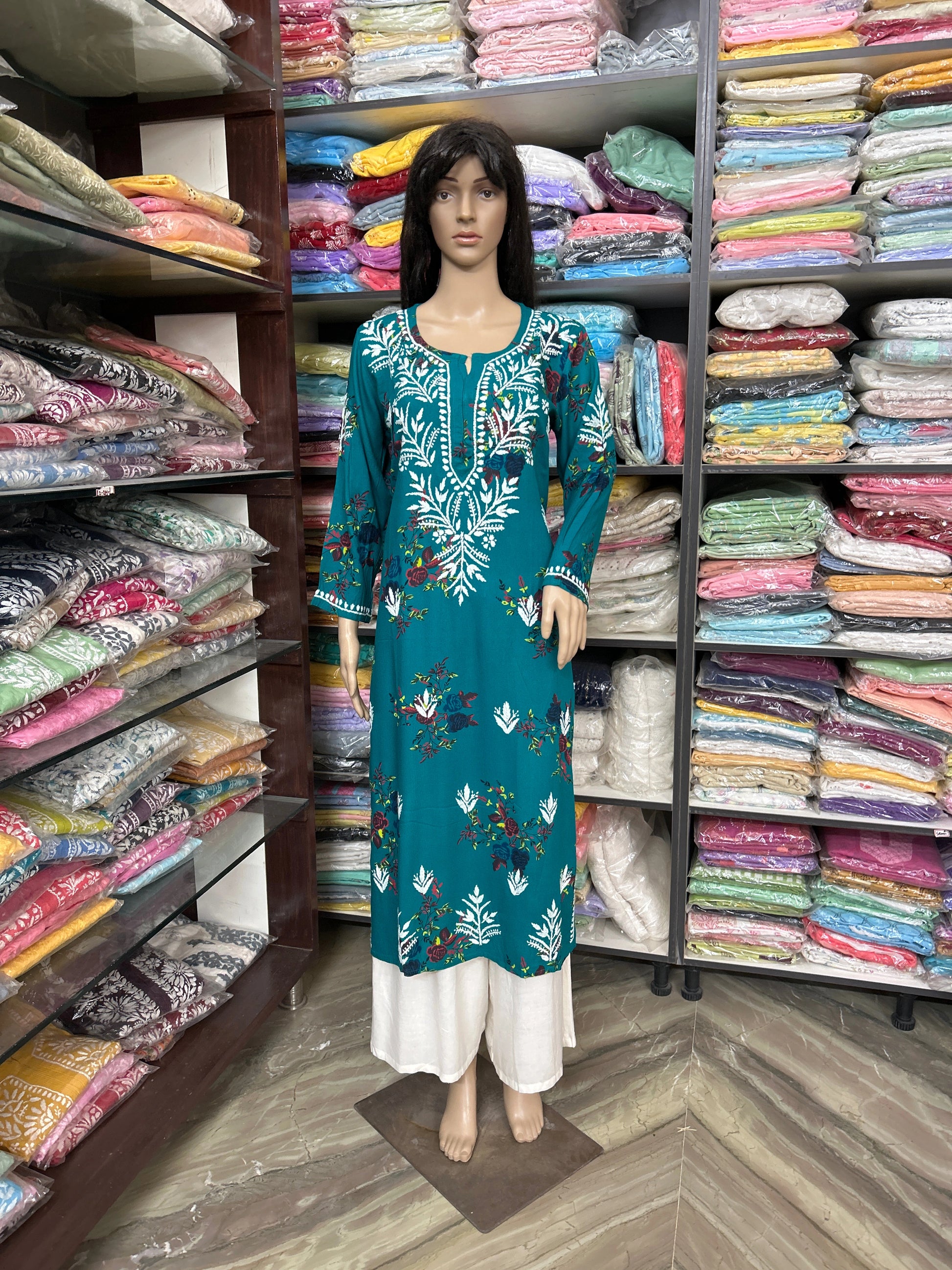 Mannequin wearing a teal embroidered dress in a fabric store