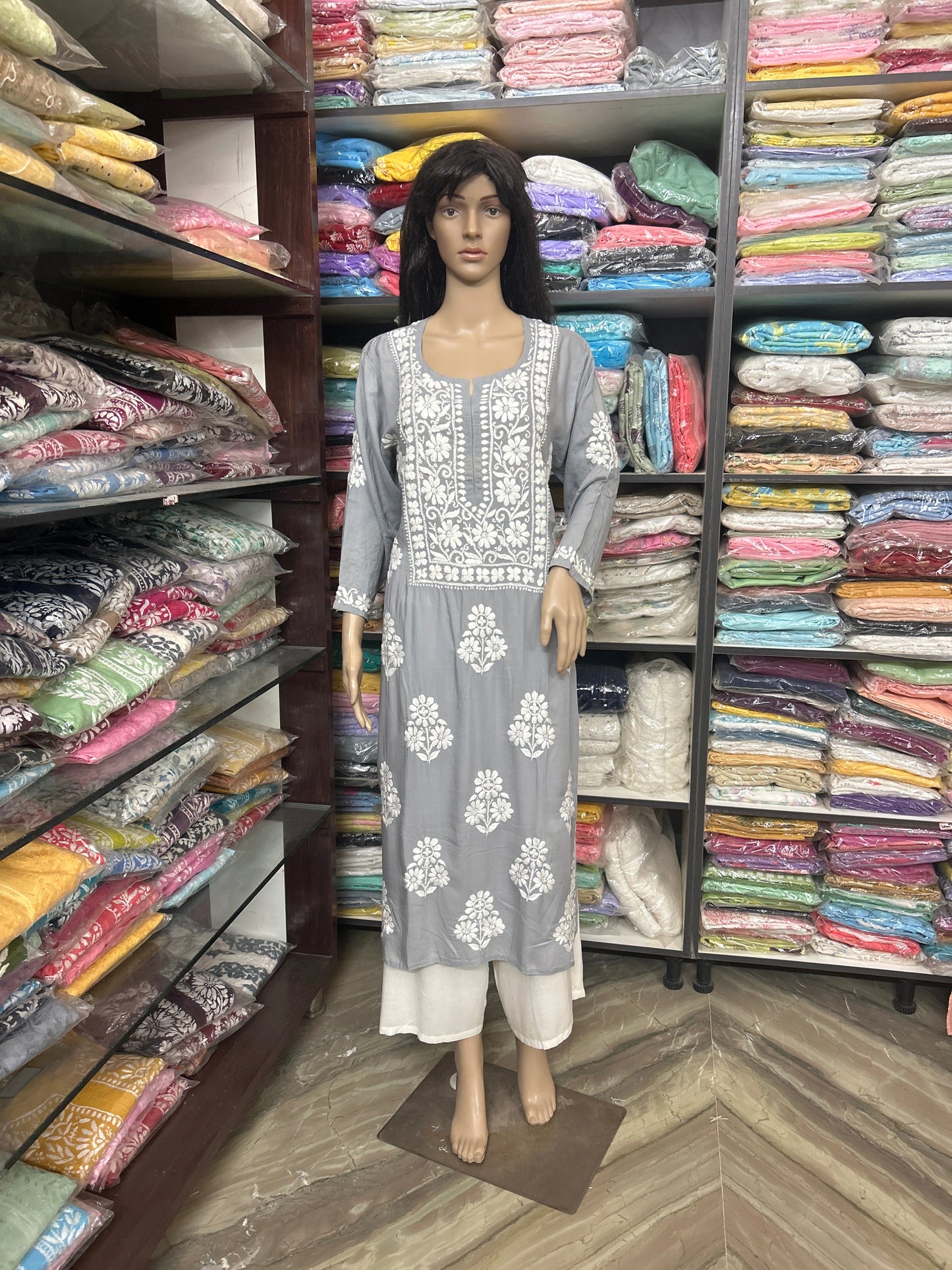 Lucknowi Chikankari Mannequin wearing a gray dress with white floral patterns in a fabric store.