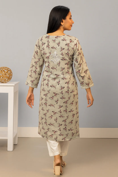 Woman wearing a blue embroidered kurta with white pants against a beige background