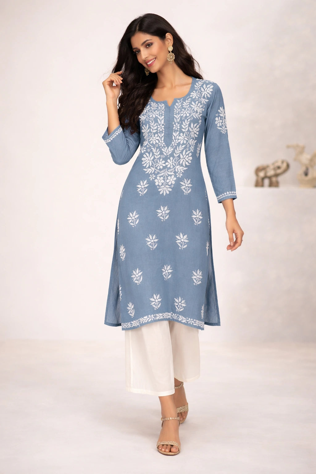 Woman wearing a blue embroidered kurta with white pants on a light background